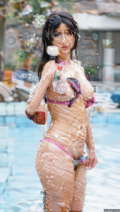 woman in a bikini standing in a pool with water spraying her face